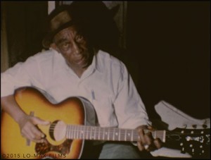 First ever color film footage of Mississippi John Hurt by K. Swerilas, here performing “Louis Collins”. Image from collection of Lo-Max Films Ltd.